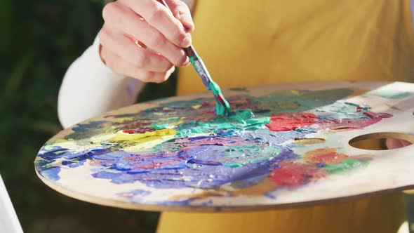 Midsection of caucasian woman painting in sunny garden