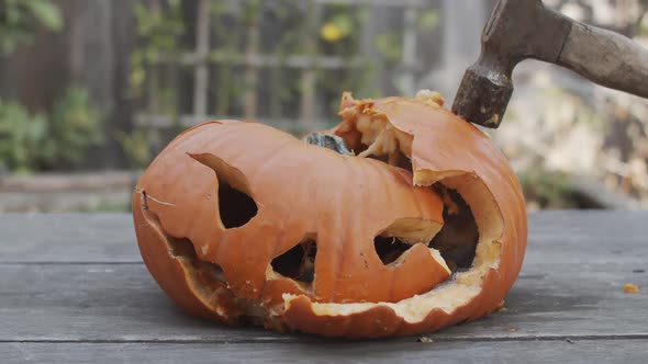 Slow motion close-up of a rotten jack-o-lantern being hit with a hammer.