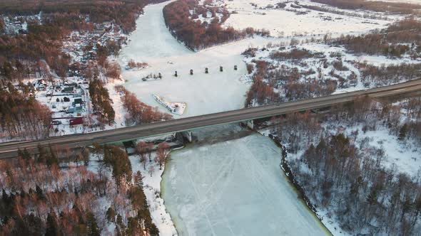 Perfect Winter Landscape with Frozen River and Bridge at Sunset Aerial View