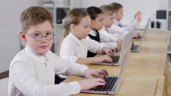 Preteen Caucasian Schoolboy in Glasses Smiling in Computer Class