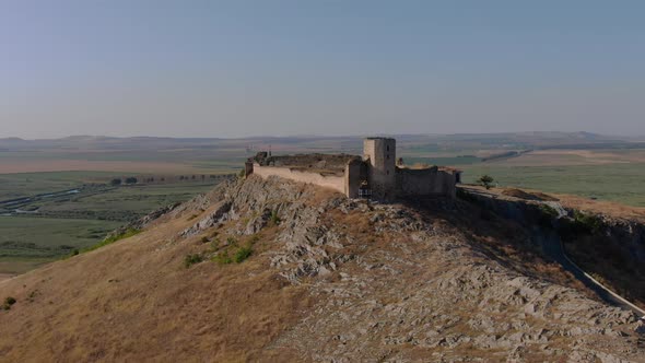 Dolly zoom shot of Enisala, medieval fortress on top of a hill surrounded by lakes and plains on a c