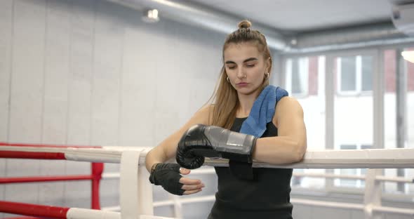 Young Woman Putting on Boxing Gloves at Gym