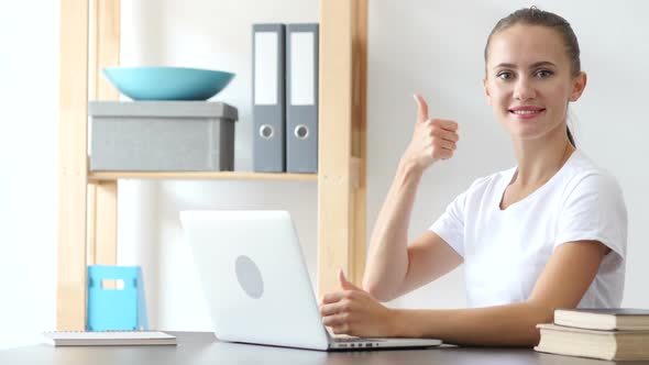 Thumbs Up Gesture By Woman at Work in Office