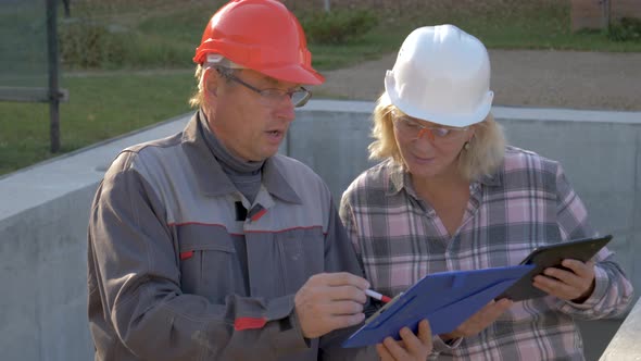Builder And Client In Helmet Discuss Construction According To Plan Project