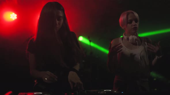 Two Beautiful Young Women DJ Play the Music on the Mixing Console in the Nightclub