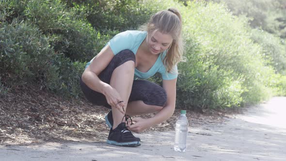 A young woman runner tying her shoes before going on a run.