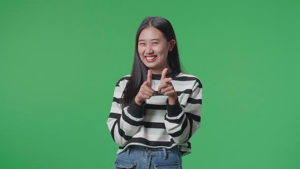 A Smiling Asian Woman Showing Gesture To Camera While Standing In Front Of Green Screen Background