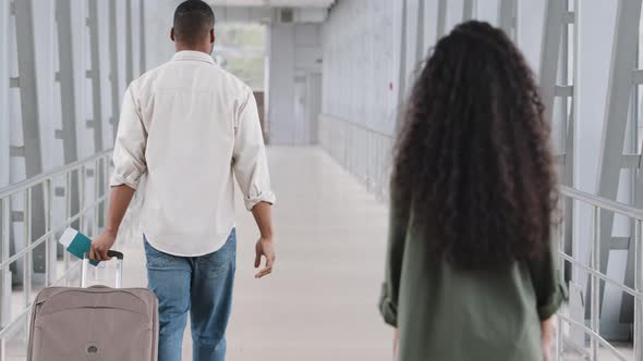 Back View Multiracial Couple Unrecognizable Curly Brunette Woman and African Man with Luggage