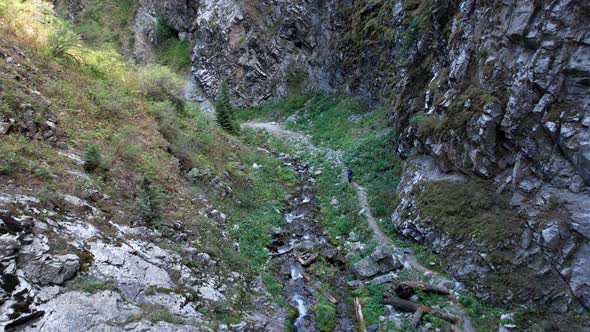 Mountain Trail in Gorge with a River and a Tourist