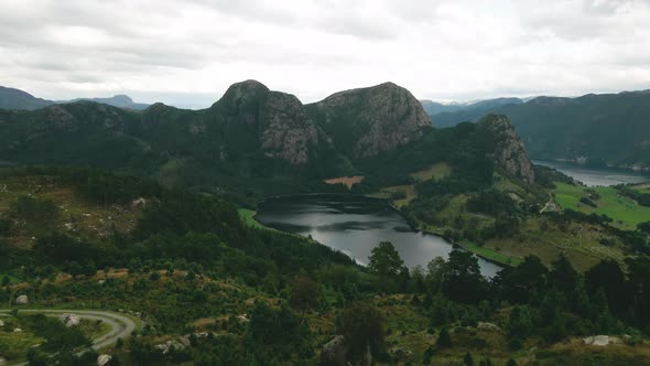 Aerial View Of Calm Lake From Above Fir Tree Farm On Mountain Hills With Crag. - pullback