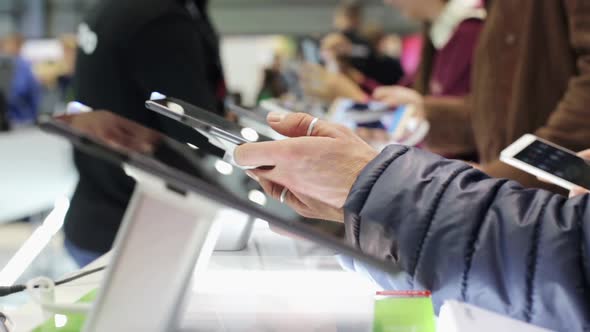 A man chooses a new tablet in a shopping center where there is a sale.