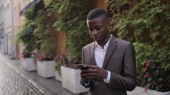 Afro American Man in Suit Using Smartphone on Street