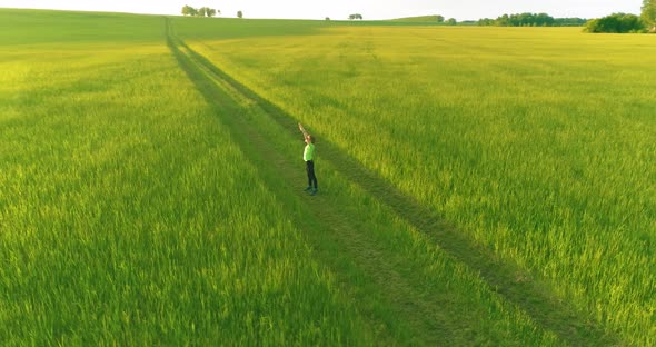 Sporty Child Standing in Green Wheat Field with Raised Hands Up. Evening Sport Training Exercises at