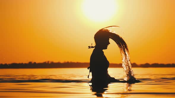 Silhouette of Woman Flipping Her Long Hair Back in Water. Slow Motion 240 Fps