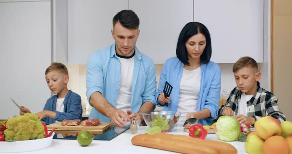 Friendly Family with Children Preparing Together Delicious Dinner in Cozy Kitchen