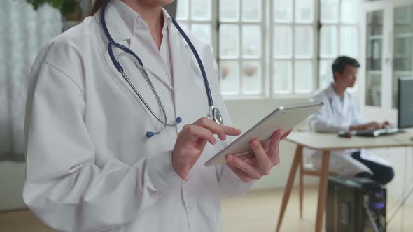 Close Up Of A Female Doctor Wearing White Coat Working On Tablet Computer At Her Office