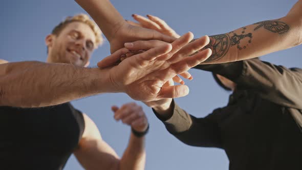 Below View of Group of Diverse People Putting Hands Together Enjoying Teamwork Outdoors Blue Sky