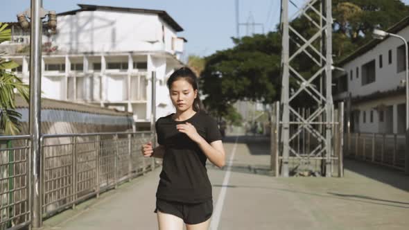 Beautiful Asian woman athlete running testing intense cardio endurance workout in the urban city.