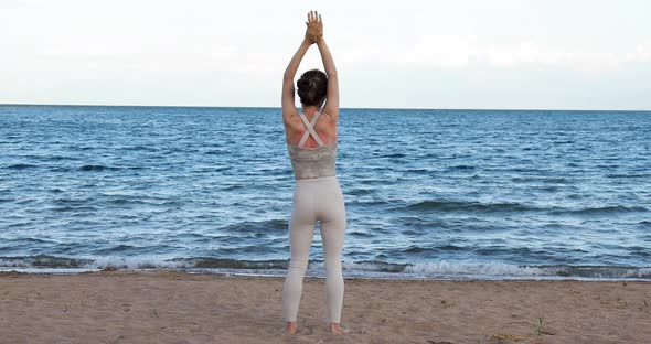 Relaxed woman stretching arms breathing fresh air on the beach, freedom concept