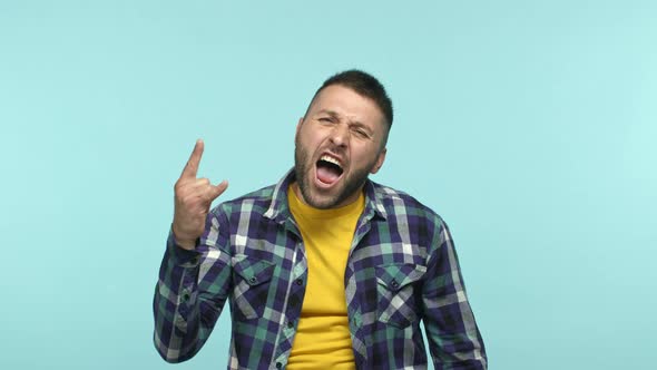 Happy Adult Guy Having Fun Enjoying Music or Event and Showing Rock n Roll Horns Gesture Shouting