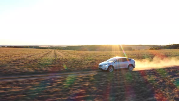 Aerial Shot of Electrical Car Moving on Offroad Route Leaving Dust Trail Behind