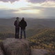 A Young Couple Stand on Top of a Mountain and Enjoy the Sunset. Hikers on a High Cliff. - VideoHive Item for Sale