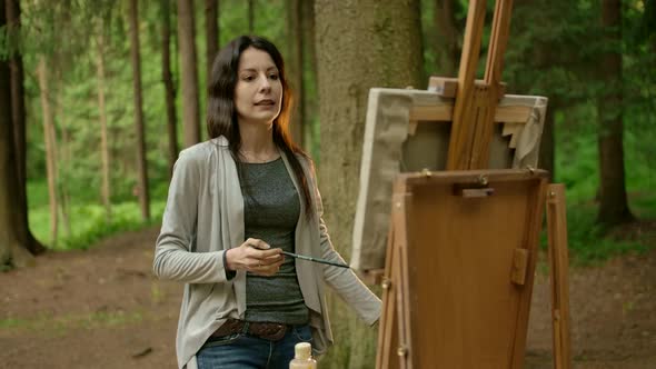 Attractive Brunette Woman Painting a Picture on Canvas in a Park