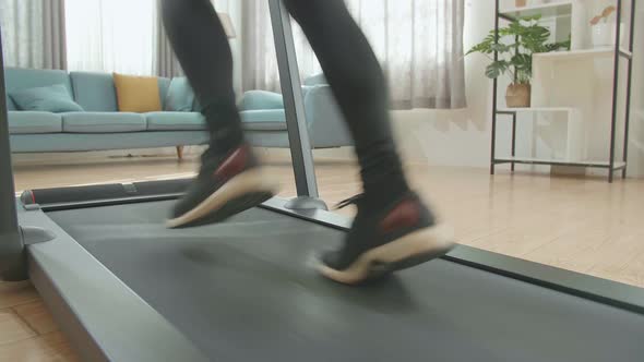 Back View Legs Of Asian Woman Running On A Treadmill At Home