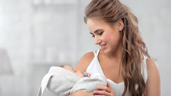 Charming Happy Young Mother Lulling Newborn Baby Feeling Togetherness and Positive Emotion