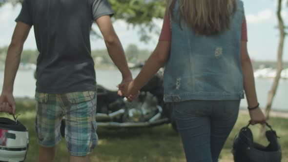 Motorcycle Couple Holding Helmets in Hands Walking