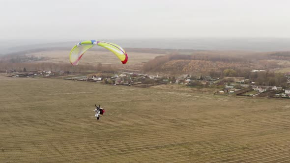 Flying parachutist near the village on a foggy day