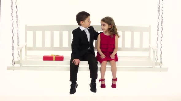 Little Boy Straightens His Hair To His Girlfriend and Embraces Her Trembling. White Background. Slow