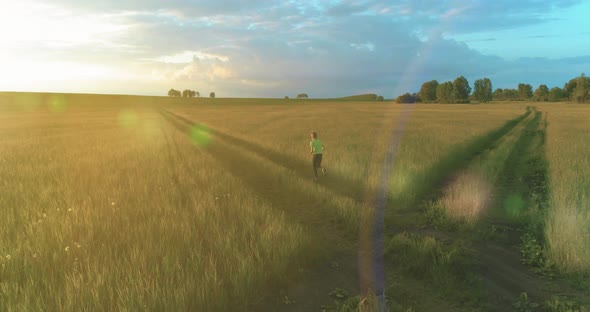 Sporty Child Runs Through a Green Wheat Field