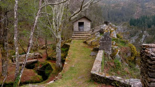 mountain hut with stone wall on the cliff of the viewpoint with a bridge and wooden tables in the pi