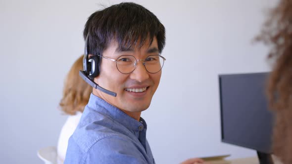 Young Asian male customer sales executives talking on headset in modern office 4k