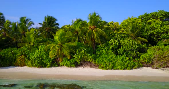 Wide angle flying abstract shot of a sandy white paradise beach and blue water background in vibrant