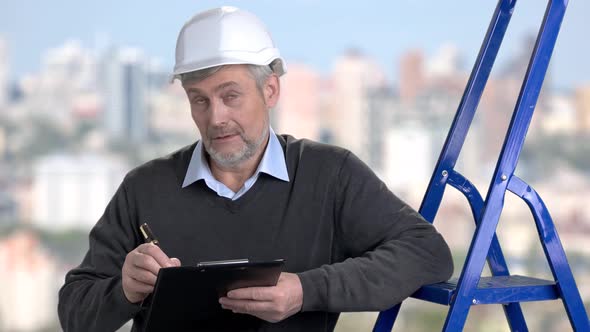 Mature Foreman Writing on Clipboard