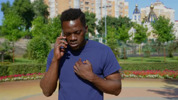 Portrait Angry AfroAmerican Man Standing in Park Talking on Mobile Phone