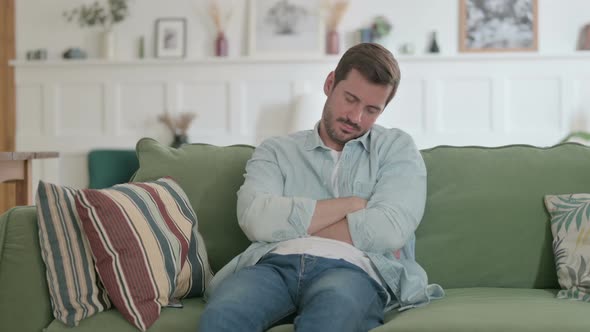 Young Man Sleepy While Sitting on Sofa at Home