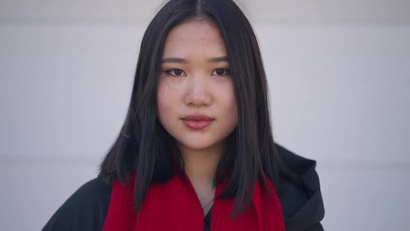 Young Asian Confident Woman Standing at White Background Looking at Camera with Serious Facial