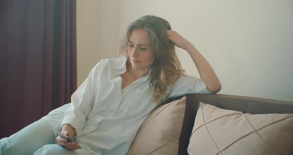 Relaxed Young Woman Holding Smart Phone Looking at Cellphone Screen Using Mobile Apps for Shopping