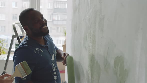 Happy Multiethnic Man and Woman Painting Room Together