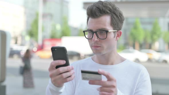 Excited Young Man Shopping Online on Smartphone Outdoor