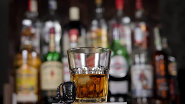 A Closeup of a Glass of Whiskey and Car Keys Slowly Rotate in a Bar