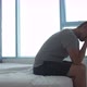 Depressed Young Man Sitting on Edge of Bed at Home or in Hotel Room - VideoHive Item for Sale