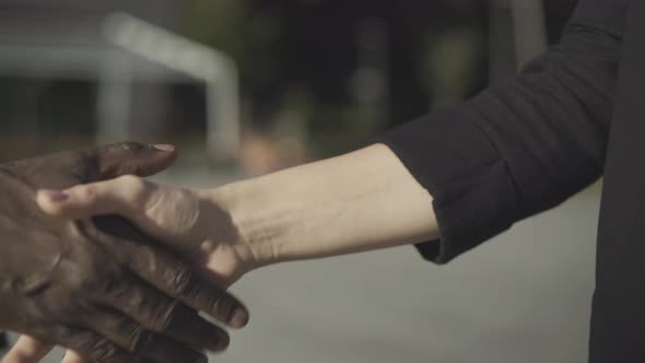 Close-up Handshake of Caucasian Woman and African American Man Outdoors. Unrecognizable Multiracial