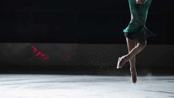 The Girl Skater Performs a Jump with the Rotation of a Triple Toe Loop in a Counter Light on an Ice