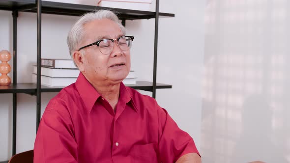 Senior Asian man participating in video call with family members.