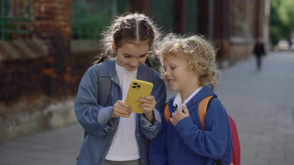 Schoolgirl Shows Mobile Game to Her Classmate on the Street