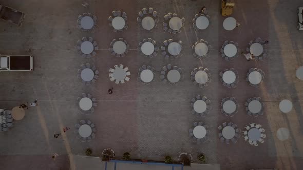 Aerial view of people preparing tables and chairs for a outdoor party in Greece.